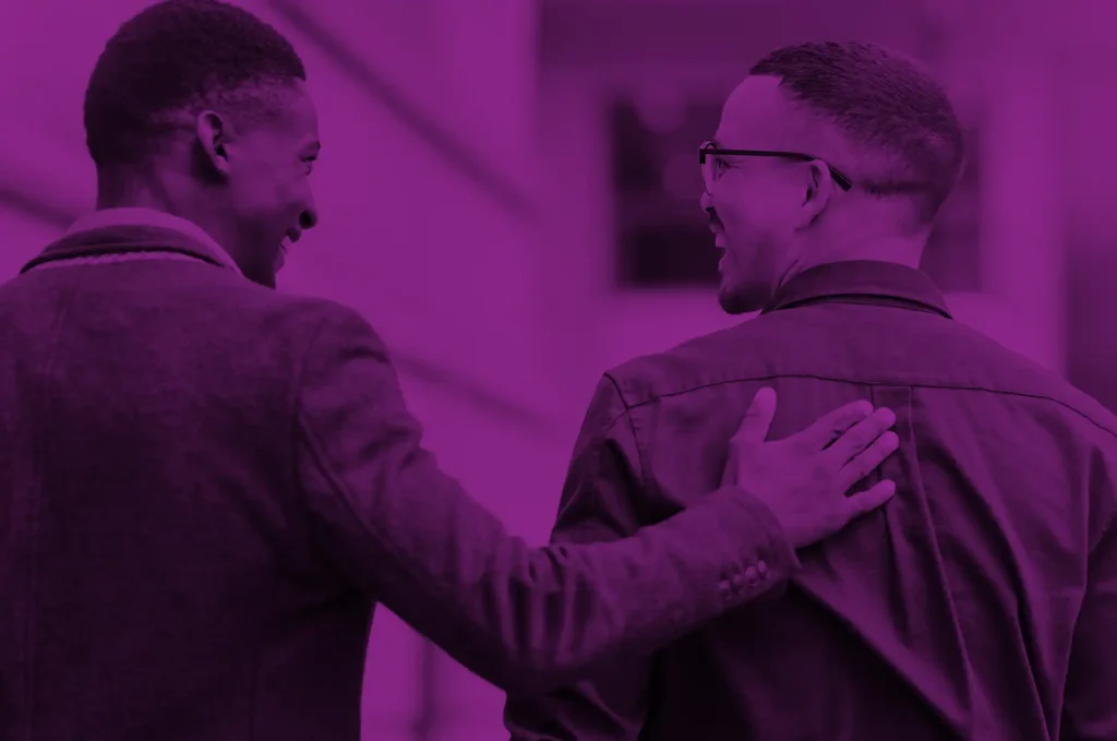 Two professionals walking together with a supportive gesture representing ongoing partnership